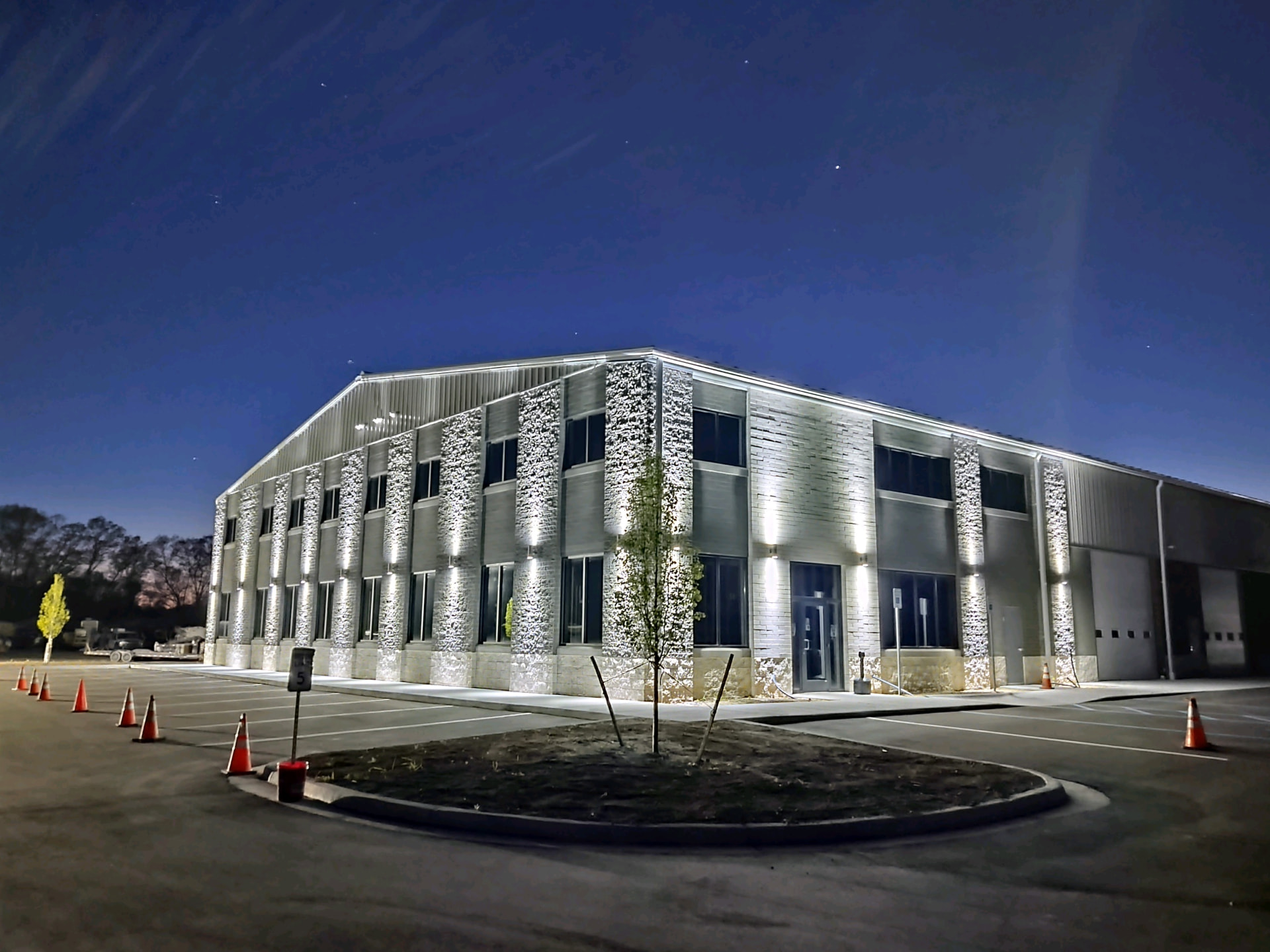 Steel office and warehouse combination with accent facade lighting, glazing bands and drive-in doors on the shop end.