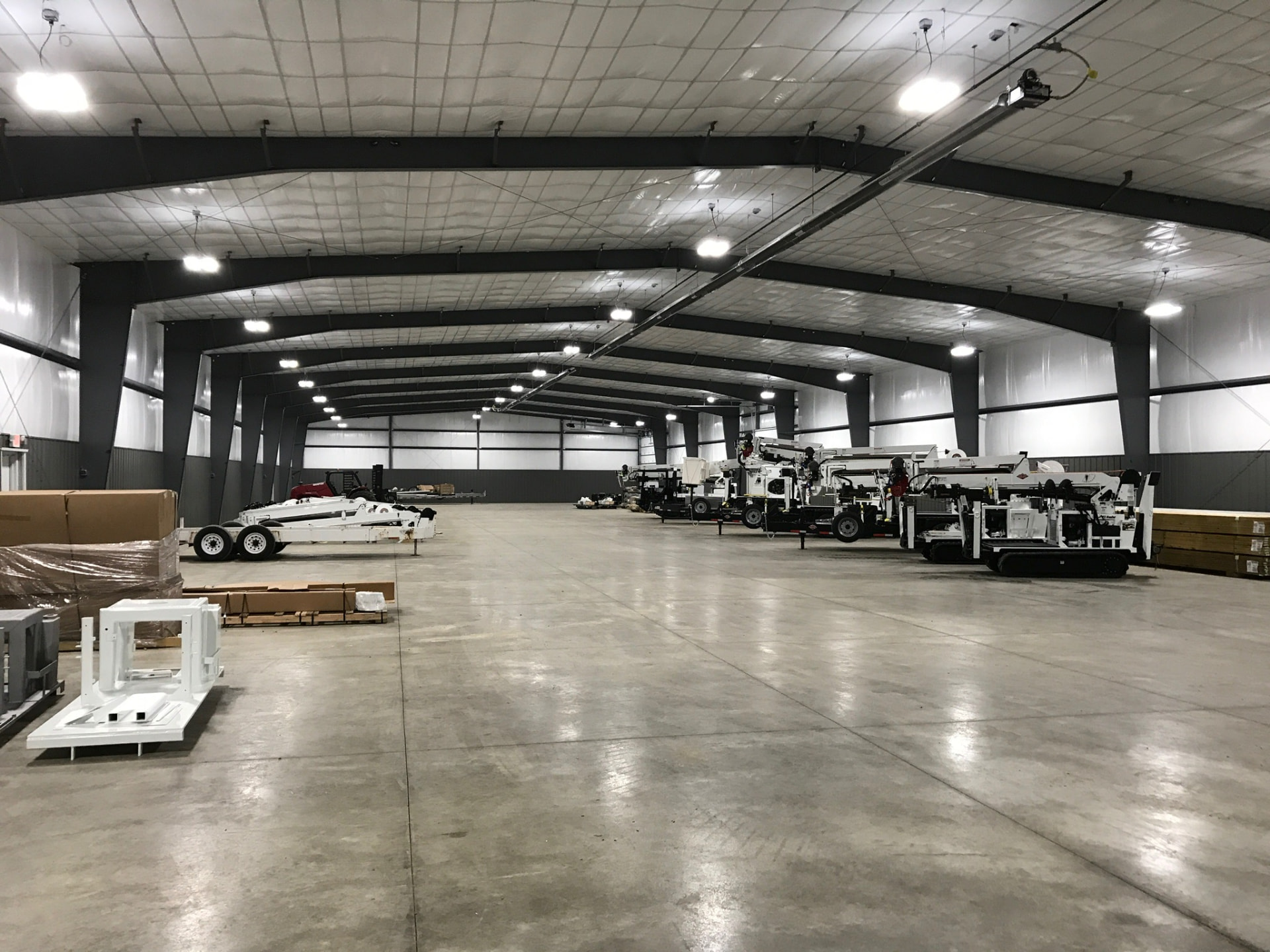 Column-free bay with insulated roof liner, charcoal wainscot and high-bay lighting for equipment storage.